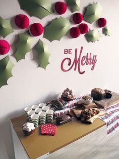 a table topped with lots of desserts next to a christmas decoration on the wall