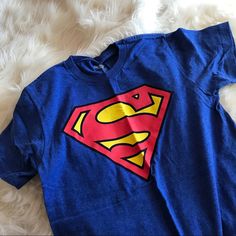 Blue Superman T Shirt With Logo Printed On The Front, Never Worn And Excellent Condition! Blue Pop Culture T-shirt With Character Print, Blue Superhero T-shirt With Character Print, Casual Blue Shirt With Character Print, Red Superhero Short Sleeve Top, Blue Cotton Pop Culture T-shirt, Blue Cartoon Print T-shirt Fan Merchandise, Blue Cartoon Print T-shirt For Fans, Blue Shirt With Logo For Fan Merchandise, Blue Short Sleeve Superhero Tops