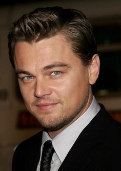 a close up of a person wearing a suit and tie with a smirk on his face