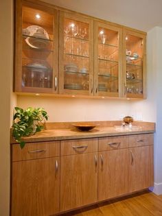 a kitchen with wooden cabinets and glass doors on the front, and an image of a potted plant in the middle