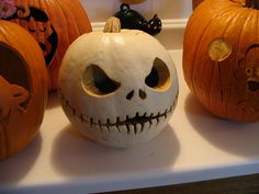 three pumpkins with carved faces on them sitting on a counter in front of other halloween decorations