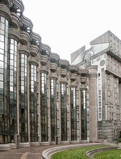 a large building with many windows on the side of it and grass in front of it