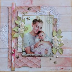 a woman holding a baby in front of a wooden wall with lace and flowers on it