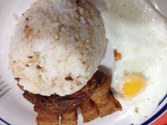 a plate with rice, fried egg and meat on it is sitting on a table