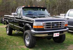 a black pickup truck parked on top of a lush green field