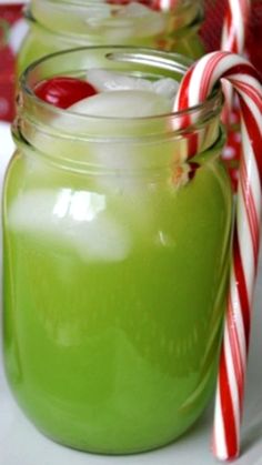 three jars filled with green liquid and candy canes