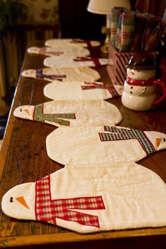 a wooden table topped with quilted snowmen on top of it