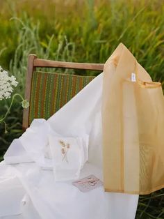 an empty chair sitting in the middle of a field with white flowers and cloths on it