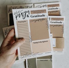 a hand is holding up some paper with different types of writing on it and there are several