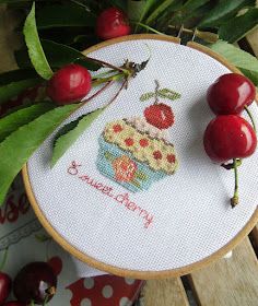 the cherries are on the table next to the embroidery