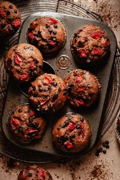 chocolate chip muffins with strawberries and chocolate chips in a baking tin on a cooling rack