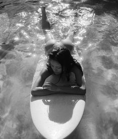 a woman laying on top of a surfboard in the water