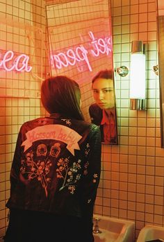 a woman standing in front of a bathroom mirror