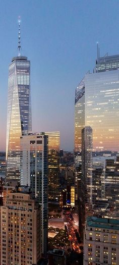 the city skyline is lit up at night, with skyscrapers in the foreground