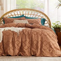 a bed with brown and teal comforters in front of a window