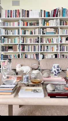 a living room filled with lots of books on top of a wooden table next to a book shelf