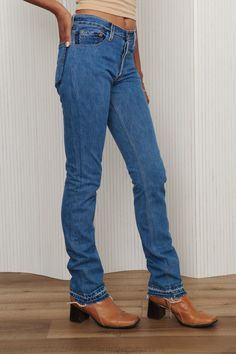 A unique pair of Levi's reworked denim jeans - featuring two tone pockets, frayed and exposed hem, and button fly. 100% Cotton. Waist: 27” - Hips: 36” - Rise: 9.5” - Inseam: 36” - Leg Opening: 7”. Fits like 26-27. Model is waist size 26. Levi's Denim Flare Jeans With Five Pockets, Fitted Bottoms With Contrast Stitching In Medium Wash, High Rise Rigid Denim Jeans With Frayed Hem, Levi's Straight Leg Rigid Denim Jeans, Levi's Rigid Denim Straight Leg Jeans, Mid-rise Denim Jeans With Contrast Stitching, Mid-rise Jeans With Contrast Stitching, Levi's Rigid Denim Bottoms With Standard Cut Leg, Medium Wash Rigid Denim Jeans With Frayed Hem