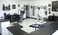 a salon with black counter tops and white tile flooring, chairs and pictures on the walls