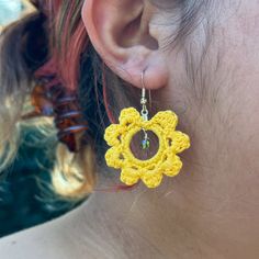 a woman wearing yellow crochet earrings and a pair of gold earwires