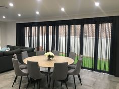 a dining room table surrounded by grey chairs and gray couches in front of sliding glass doors