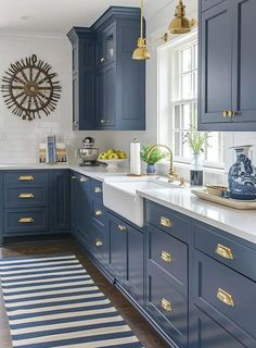 a kitchen with blue cabinets and gold pulls on the handles, along with a striped rug