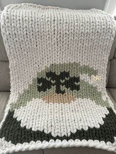 a crocheted blanket sitting on top of a couch next to a pillow that has an image of batman