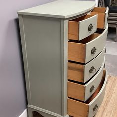 an old dresser with drawers is painted gray and has wood trim on the bottom drawer