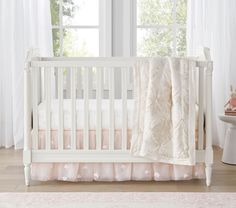 a white crib with pink bedding and curtains