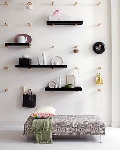 a white room with black shelves and various items on the wall, including a bench