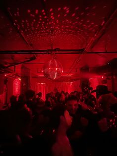 a group of people in a room with red lights and disco balls hanging from the ceiling