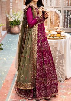 a woman in a purple and green lehenga standing next to a table with food