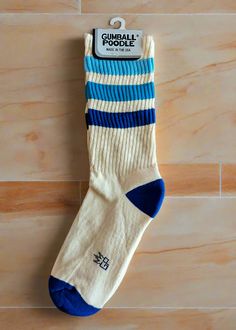 Takin' it back to the '70s and '80s with these retro socks! Features a more relaxed fit for ultimate comfort and a gentle feel around the calf. Wear them pulled up or scrunched down. Made of natural cotton with accents of royal blue cotton, Columbia blue nylon, and factory blue nylon. Super comfy, unisex, one-size-fits-most, and made in the USA. Features: Unisex Gym Crew Socks Wide Rib knit Cushioned foot = extra comfort! Seamless toe Cream colorway with variated blue stripes Leg height: 8" unstretched (measured from heel seam to cuff) USA made Brand & Fabric Content: Brand: Gumball PoodleMaterials: 61% cotton 36% nylon 3% spandex | Machine wash cold, line dryMade in: USA Fit: Wide ribbed socks reach to mid-calf on most folks & fit a women’s US size 6 to men’s size 15. As a thicker weave, Retro White Cotton Socks, White Cotton Retro Socks, Stretch Cotton Socks In Beige, Stretch Beige Cotton Socks, Beige Stretch Cotton Socks, Blue Cotton Socks For Summer, Blue Cotton Sporty Socks, Beige Cotton Socks For Summer, Retro Socks