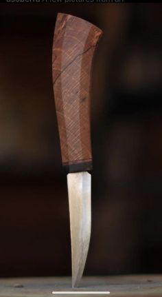 a knife that is on top of a wooden block with a blade sticking out of it