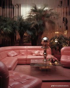 a living room filled with lots of pink couches and tables in front of palm trees