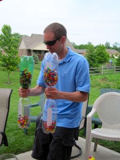 a man holding two bags filled with candy on top of a table in the grass