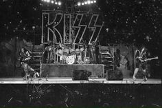 the band kiss performing on stage in black and white with snow falling all over them