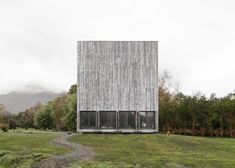 a tall wooden building sitting on top of a lush green field next to trees and bushes