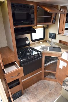 a kitchen area with an oven, sink and microwave in a recreational vehicle or trailer