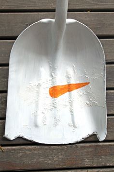 a white spatula with an orange carrot painted on it sitting on a wooden table