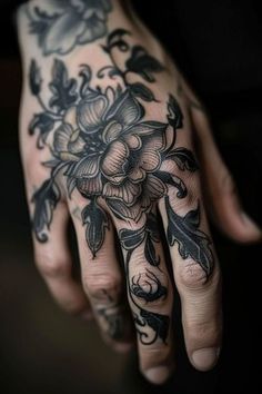 a woman's hand with black and white tattoos on it, holding a flower