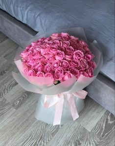 a bouquet of pink roses sitting on top of a white box next to a bed