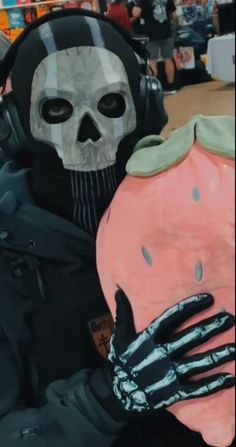 a person wearing a skeleton mask and holding a pink piggy bank in front of them