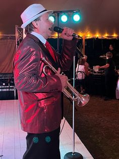 a man in a suit and hat singing into a microphone