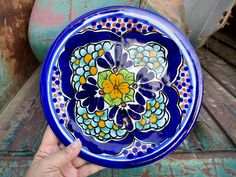 a hand holding a blue and yellow plate on top of a rusted metal surface