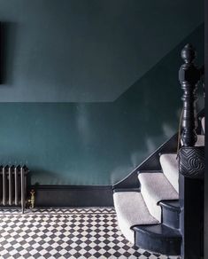 a black and white checkered floor in a green room with stairs leading up to it