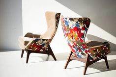 two colorful chairs sitting next to each other on a white floor in front of a wall