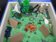 an open bin filled with lots of toys and other items on top of green grass