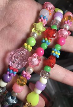 a person holding several different colored beads in their hand and the beaded bracelet is attached to them