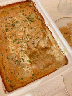 a casserole dish in a white plastic container with green garnish on top