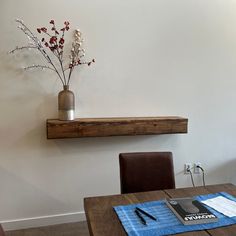 a wooden table topped with a vase filled with flowers next to a wall mounted shelf